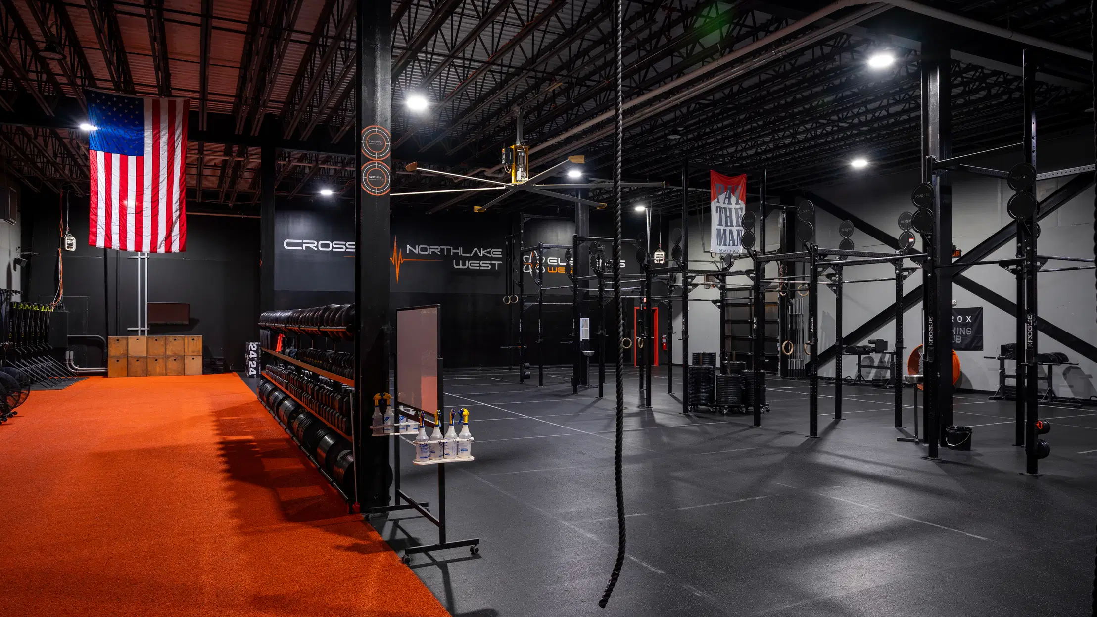 QC Fit West training floor with strength equipment, rig stations, and orange turf